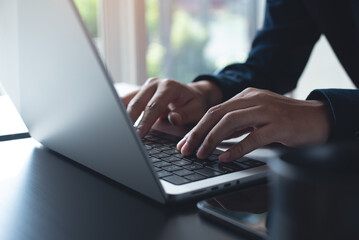 Business man hands typing on laptop computer keyboard, searching information, surfing the internet on dark office desk, distance job, online working, business and technology concept