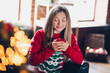 © deagreez - Portrait of satisfied relaxed teenager with blond hair dressed red sweater smell aroma coffee on christmas morning in house indoors
