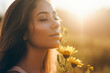 Woman smelling flower in sunlight.