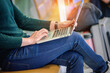 © Chanyanuch - An Asian young  man wearing green color wool sweater and using laptop at the  airport terminal  while waiting for boarding time, soft focus, travelling concept.