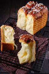 Wall Mural - Butter brioche bread sprinkled with pearl sugar on black grille on a dark wooden background.  Wheat bread recipes.