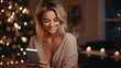 Young woman talking and smiling to her boyfriend via video call on a smartphone at home, blurred living room with festive Christmas lights and candles on background
