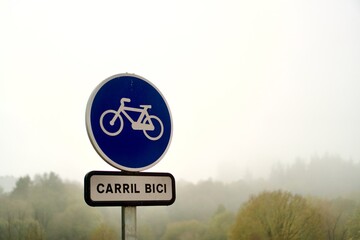 bike lane sign in Spanish carril bici with copy space and a foggy background on a winter day. Sustainable mobility concept in bad weather