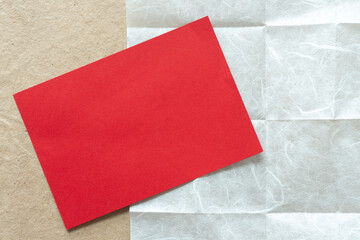 Wall Mural - blank grungy red card positioned at an angle on tissue paper with crease marks on plain brown paper