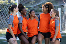 Female Soccer Team. The Women Players Work Together As A Team In A Group Of Five Wearing Matching Orange Jerseys. 