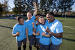 © Mat Hayward - Soccer players wearing blue jerseys. The team is celebrating and the men are happy shouting and giving high fives after a score during a game.