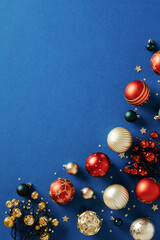 Abstract Christmas background with baubles and branches of berries on dark blue table.