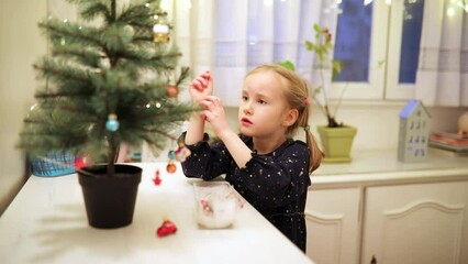 Wall Mural - Adorable preschooler girl decorating little Christmas tree with miniature toys at home