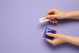 Fototapeta  - Woman holding condom and contraceptive pills on violet background, top view with space for text. Choosing birth control method