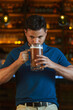 © TTLEstebanRivera - Hombre latino con una cerveza en un bar con colores calidos. con espacio para copy y diseños con expresiones