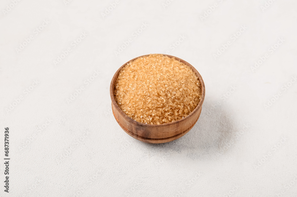Bowl with brown cane sugar on white background