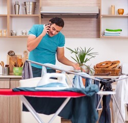 Wall Mural - Young man husband doing clothing ironing at home