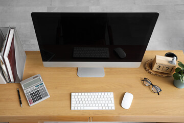 Blank computer monitor with calculator on table in office, top view