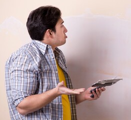 Wall Mural - Young man applying plaster on wall at home