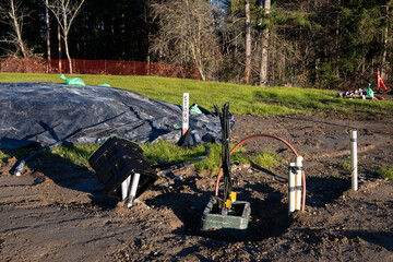 Freshly dug up ground and in progress installation of underground utilities on a new residential community construction site
