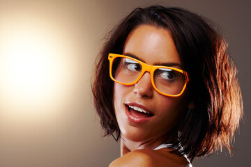 Woman, face and closeup with glasses in studio for vision, sight and trendy fashion mock up on brown background. Female model, confident or pose for wow, surprise or omg for cool, chic or spectacles