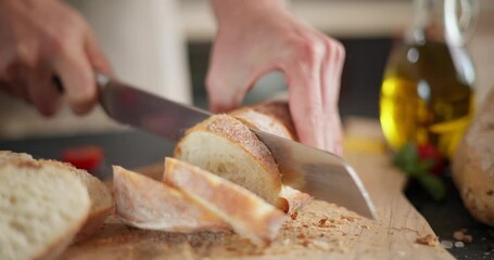 Canvas Print - Woman slicing baguette bread on a wooden cutting board at domestic kitchen close-up