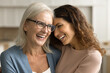 © fizkes - Cheerful loving senior mom in glasses and pretty adult daughter woman hugging with emotional heads touch, laughing with closed eyes, smiling, enjoying talk, family connection, closeness