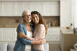 © fizkes - Cheerful dreamy elder mom and positive adult daughter woman hugging at home with love, support, looking away, smiling, thinking on family relationships, bonding, discussing mothers retirement plans