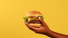 Yummy Fast Food Burger. African American Male Hand Hold Tasty Hamburger On Yellow Background. Unhealthy Junk Food Concept. Fresh Hot Cheeseburger. Lunch Snack Delivery. McDonalds Fastfood.