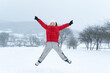© somemeans - Child with his hands up and enjoys the winter holidays. Teenage boy in red jacket jumps during snowfall