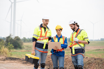 Wall Mural - Group of male and female engineer working at wind turbines farm, discussing and inspecting quality wind turbines, planing maintenance of wind turbines at windmill field farm