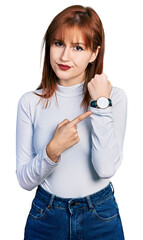 Sticker - Redhead young woman wearing casual turtleneck sweater in hurry pointing to watch time, impatience, looking at the camera with relaxed expression