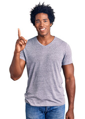 Wall Mural - handsome african american man with afro hair wearing casual clothes showing and pointing up with fin