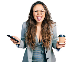 Canvas Print - Young hispanic girl using smartphone and drinking a cup of coffee sticking tongue out happy with funny expression.