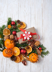 Poster - Christmas holiday background. festive decor, gift box, cinnamon, nuts, cones, decorated oranges, fir branches on white wooden table. festive winter season. top view