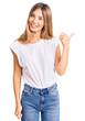 © Krakenimages.com - Beautiful caucasian woman with blonde hair wearing casual white tshirt smiling with happy face looking and pointing to the side with thumb up.