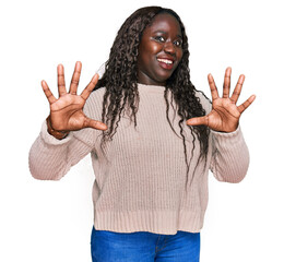 Wall Mural - Young african woman wearing wool winter sweater afraid and terrified with fear expression stop gesture with hands, shouting in shock. panic concept.