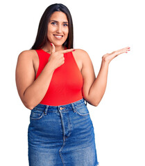 Sticker - Young beautiful brunette woman wearing casual sleevelss t-shirt amazed and smiling to the camera while presenting with hand and pointing with finger.