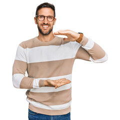 Sticker - Handsome man with beard wearing casual clothes and glasses gesturing with hands showing big and large size sign, measure symbol. smiling looking at the camera. measuring concept.