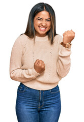 Canvas Print - Young latin girl wearing wool winter sweater celebrating surprised and amazed for success with arms raised and eyes closed. winner concept.