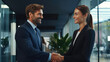 © MP Studio - A woman and a man in suits shake hands in the office