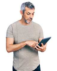 Wall Mural - Middle age hispanic with grey hair using touchpad device depressed and worry for distress, crying angry and afraid. sad expression.