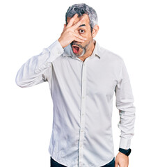 Canvas Print - Middle age hispanic with grey hair wearing casual white shirt peeking in shock covering face and eyes with hand, looking through fingers with embarrassed expression.