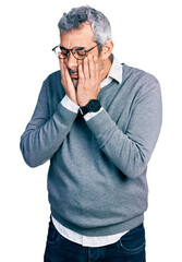 Sticker - Middle age hispanic with grey hair wearing glasses with sad expression covering face with hands while crying. depression concept.