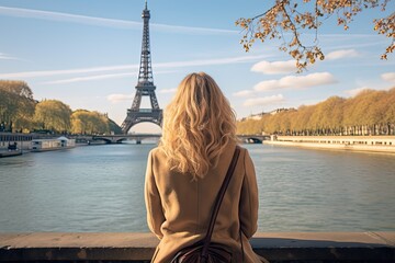 Canvas Print - Young woman looking at Eiffel Tower in Paris, France, Young traveler woman rear view sitting on the quay of Seine River looking at Eiffel Tower, AI Generated