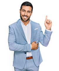 Wall Mural - Young hispanic man wearing business jacket smiling happy pointing with hand and finger to the side