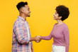 © ViDi Studio - Young couple two friends family man woman of African American ethnicity wear casual clothes together hold hands folded handshake gesture isolated on plain yellow background. Friendship greet concept.