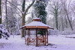 Drewniana altana w stylu japońskim w parku w Iłowej. Jest zima. Dach altany, pobliskie drzewa i ziemię pokrywa warstwa śniegu.