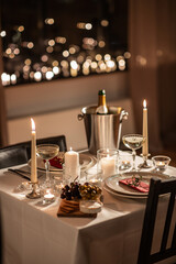 Wall Mural - holidays, romantic date and celebration concept - close up of festive table serving for two with champagne bottle in ice bucket and candles burning at home on valentine's day