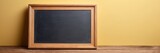 Fototapeta Sypialnia - 
Empty blackboard with wooden frame on wooden table over yellow background.