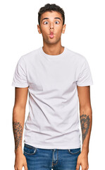 Sticker - Young handsome african american man wearing casual white tshirt making fish face with lips, crazy and comical gesture. funny expression.