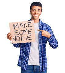 Wall Mural - Young african amercian man holding make some noise banner smiling happy pointing with hand and finger