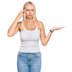 Sticker - Young blonde girl wearing casual style with sleeveless shirt confused and annoyed with open palm showing copy space and pointing finger to forehead. think about it.