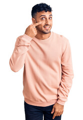 Poster - Young hispanic man wearing casual clothes pointing with hand finger to face and nose, smiling cheerful. beauty concept