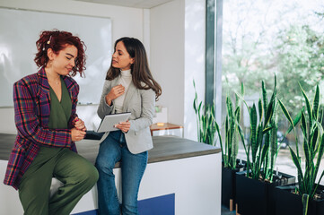 Two female executives examining business plan on a tablet at office.